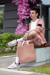 portrait of young man in trendy summer clothes with bag on street on sunny day in summer, concept of trendy urban summer clothes, youth trend
