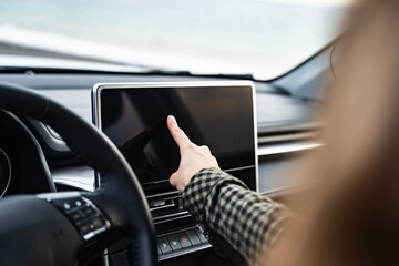 Side view of an unrecognizable woman using a GPS navigation system while driving her car. Female...