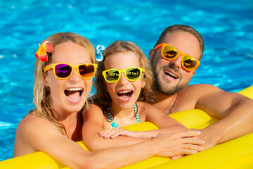 Happy family having fun in swimming pool. Mother, father and child on summer vacation