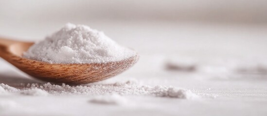 Powdered sugar on wooden spoon with scattered sugar on surface highlighting texture and fine granules in a minimalist setting