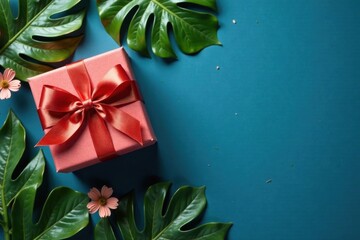 A coral gift box with a vibrant red ribbon, nestled amongst lush green tropical leaves on a teal background, evokes a sense of celebration and natural beauty.