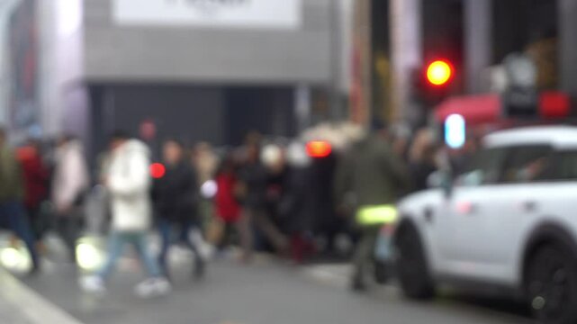 blurry video shot of city street in Milan with multitude crowd of people crossing the road on pedestrian crossings and heavy traffic of cars during fashion week - out of focus lifestyle in downtown 
