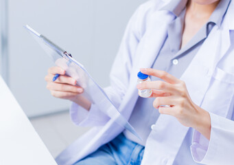 Asian professional female scientist, medical woman researcher with Vaccine Ampoule examining testing at laboratory. Woman doctor looking at blood test tube working on vaccination development.