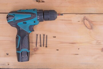 Electric screwdriver and drill on a wooden surface. Carpenter's tool for working with wood.