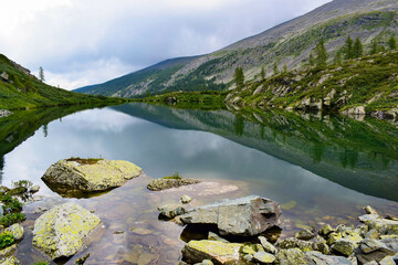 clear mountain lake with rocks and forested hills