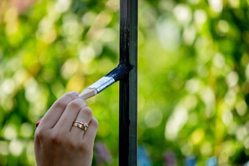 close up of painting metal with brush in garden.