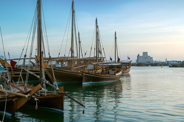 Dhows moored off Museum Park in central Doha, Qatar, Arabia, with some of the buildings from the city's commercial port in the background.