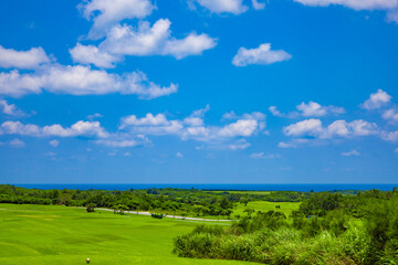 爽やかな南国の青空と青い海・リゾートのゴルフ場と奥に広がる街並みの風景（沖縄県宮古島市）