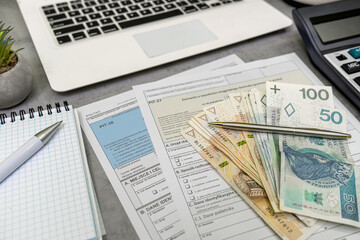 Obraz premium Polish tax forms PIT-38, PIT-36 PIT-37 polish tax form, pln zloty money pen laptop on desk
