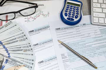1040 us Tax forms, pen calculator and dollar money glasses on the table. Taxation, paying the tax rate. April time