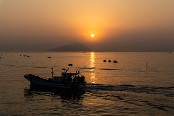 Naklejka premium fishing boat on the sea during sunrise