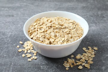 Composition with oatmeal flakes on gray background. Cooking breakfast