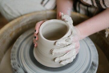 Close-up of hands shaping clay on a pottery wheel, capturing the art of pottery