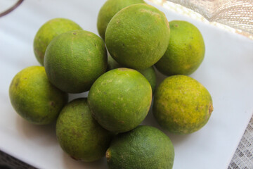 several whole limes on a white plate	