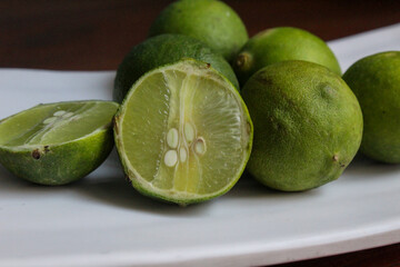 several whole limes on a white plate	
