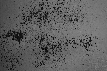 The photo shows a grey wall with splashes, streaks and blots of black paint
