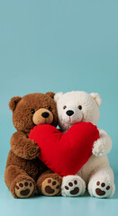 Vertical photo of a brown and a white teddy bear holding a red heart against a plain pastel blue studio background. Copy space for text. A couple of bear plush toys. For Valentine's day