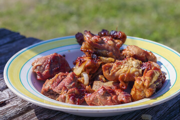
a plate of tasty meat dish served on a wooden surface with green grass in the background.