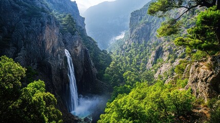 Fototapeta premium Majestic waterfall cascading down rocky cliffs in a lush green canyon