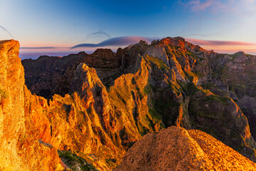 Pico do Arieiro mountain trail, Madeira island, Portugal. Panoramic photo in the mountains at sunrise. Rocks illuminated by the morning sun