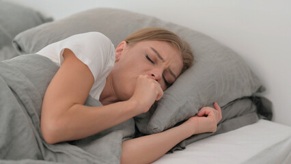 Sick Young Woman Coughing while Lying on Side in Bed