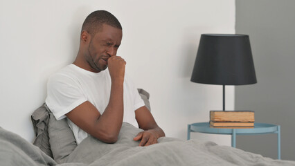 Sick African Man Coughing while Sitting in Bed