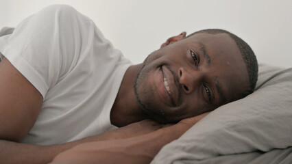 Close up of Smiling African Man Lying on Side in Bed