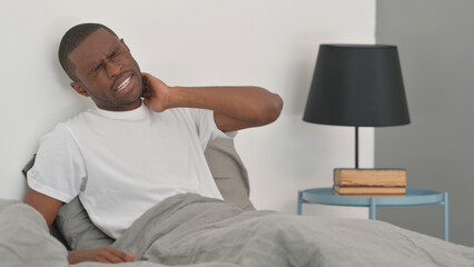 African Man with Neck Pain Sitting in Bed