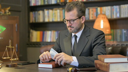 Upset Middle Aged Lawyer Counting Money in Office