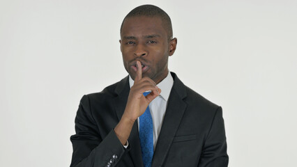 Portrait of Threatening African Businessman with Finger on Lips on White Background