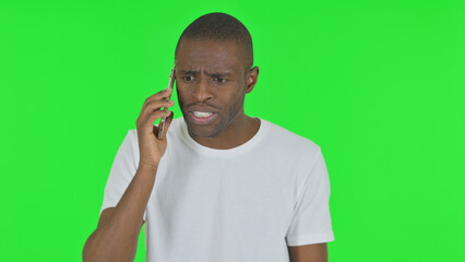 Portrait of Angry African Man Talking on Phone on Green Background