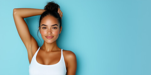 Obraz premium A young woman with her hair in a bun smiles confidently against a bright blue background