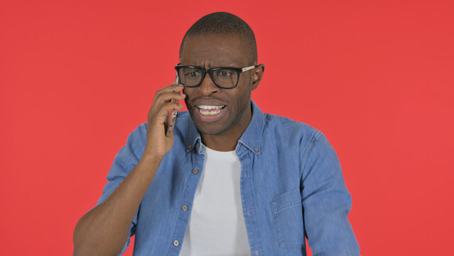Angry Casual African Man Talking on Phone on Red Background, Portrait - Powered by Adobe