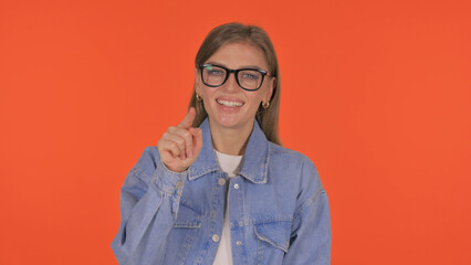 Casual Young Woman Pointing at Camera on Orange Background, Portrait