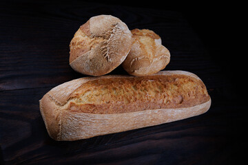 Two beautiful baguettes on a dark wooden background. Sliced bread. Art bread.