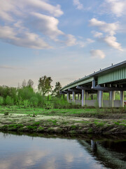 Fototapeta premium Bridge spans a river with a green forest on either side