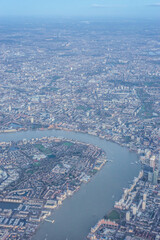 Aerial view of London through early morning clouds with Thames river flowing at golden hour sunrise near Tower Bridge
