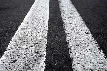 Double solid line on the road. Two white stripes on the asphalt road. Perspective view of the white lines. Empty road.