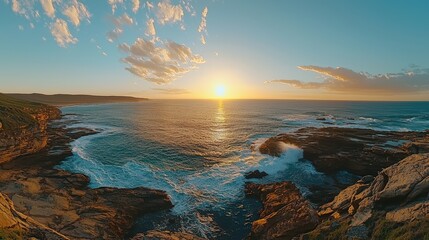 Golden sunset over rocky coastline, casting warm reflections on tidal pools and waves.