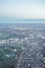 Fototapeta premium Aerial view of London outskirts suburbs through early morning clouds with Thames river flowing at golden hour sunrise near industrial area