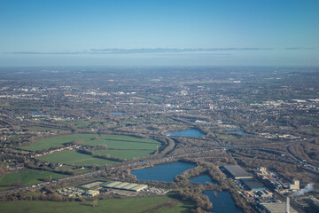 Aerial view of London outskirts suburbs through early morning clouds with Thames river flowing at golden hour sunrise near industrial area