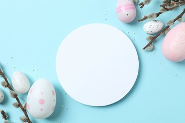Colorful eggs and pussy willow branches on a pastel blue background, space for text or advertising