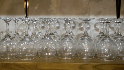Empty wine glasses drying upside down on wooden shelf