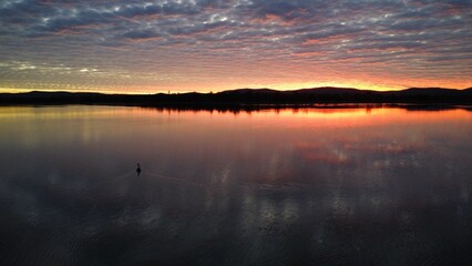Pelican at Dusk Over Reflective Lake