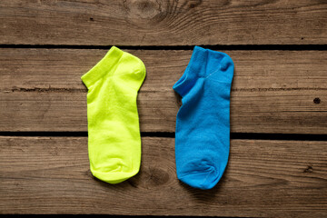 Two short women's socks one yellow one blue are lying on the floor at home