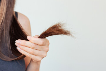 A young pretty brunette woman suffering of split ends on her long hair. Empty space