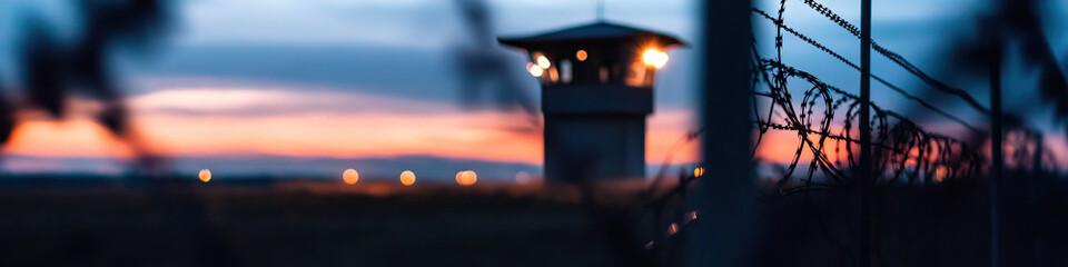 Sunset View of a Guard Tower and Barbed Wire Fence