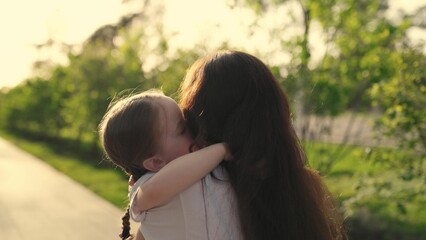 little child runs hug his mother. happy family. mom daughter child hugging park. kid kisses his...