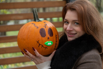 Woman holding a creatively designed pumpkin for Halloween celebration