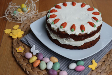 Homemade carrot cake with mascarpone cream cheese icing and mini marzipan carrot decorations with Easter eggs and decorations